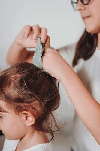 Bambina gioca indossando uno scrunchie in tessuto naturale.